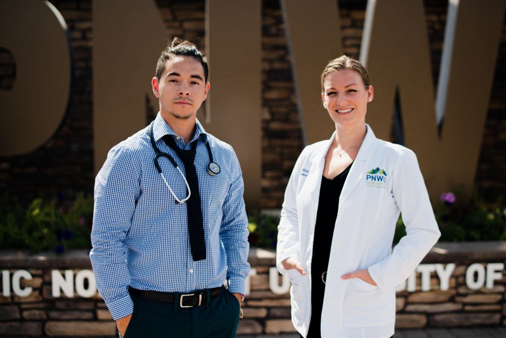 Two student doctors in front of PNWU sign